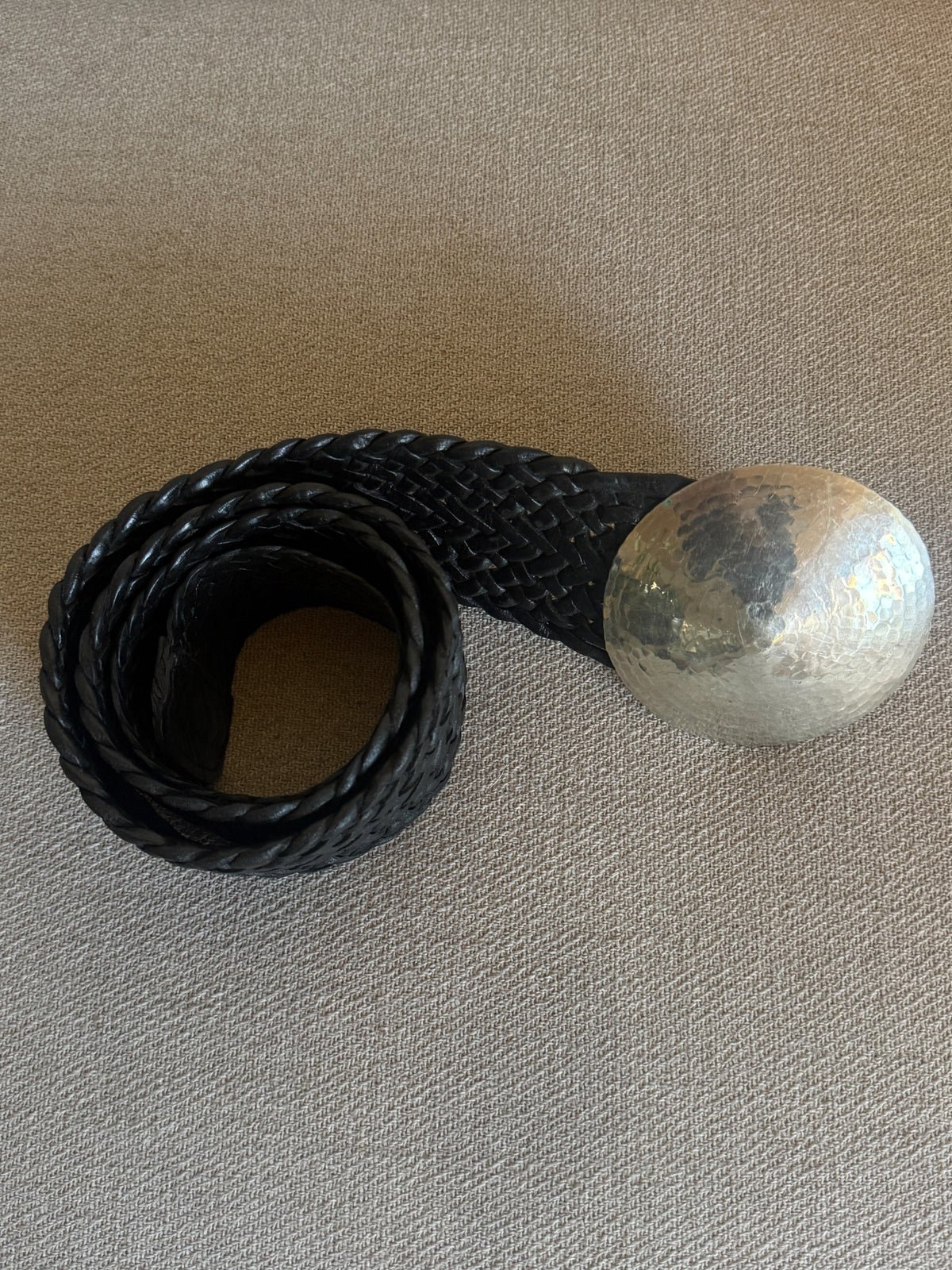 Black braided leather belt and oversized round hammered silver-tone buckle