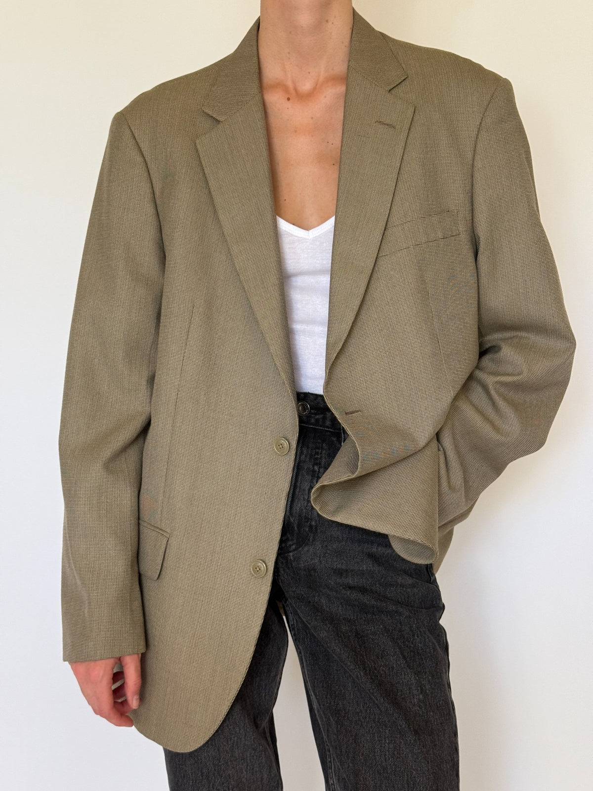Angled front view of beige patterned blazer with black denim