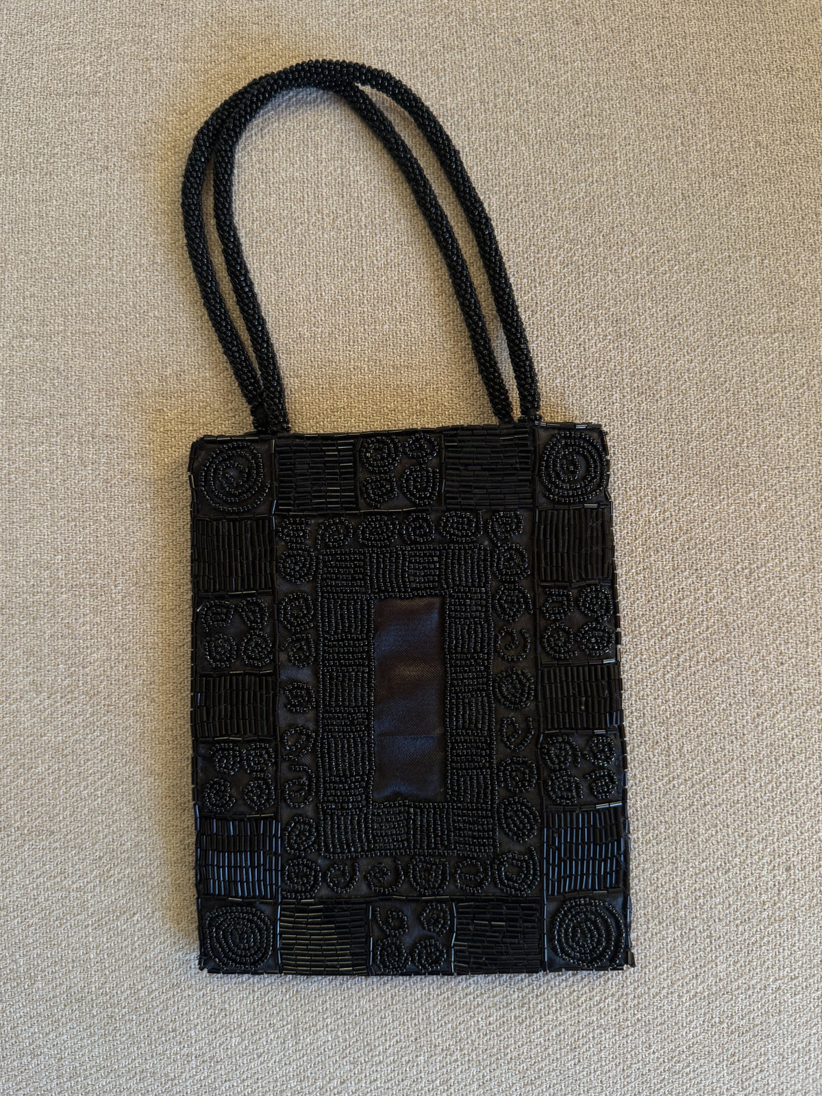 Black beaded shoulder bag displayed on stand