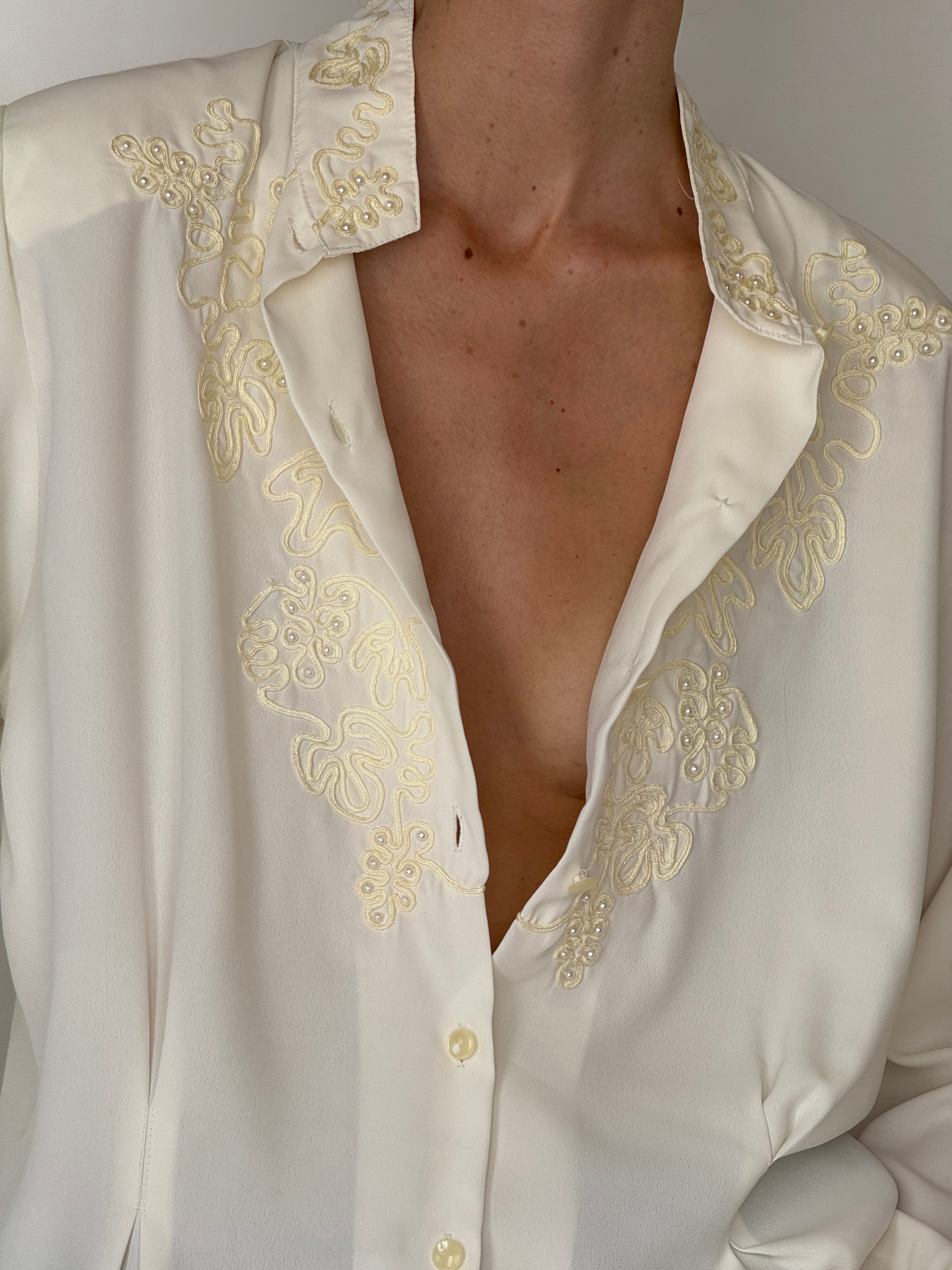 Vintage ivory blouse fabric close-up with embroidery