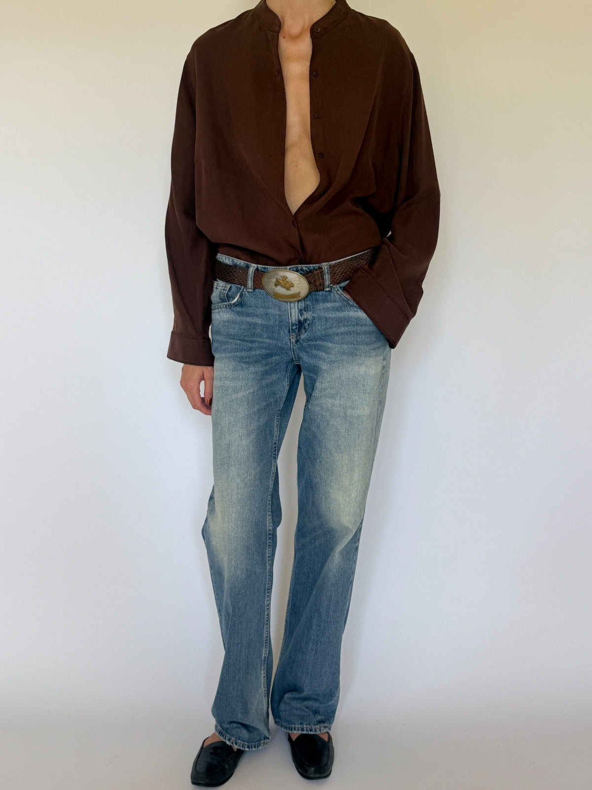 Front view of chocolate brown silk mandarin collar shirt tucked into jeans