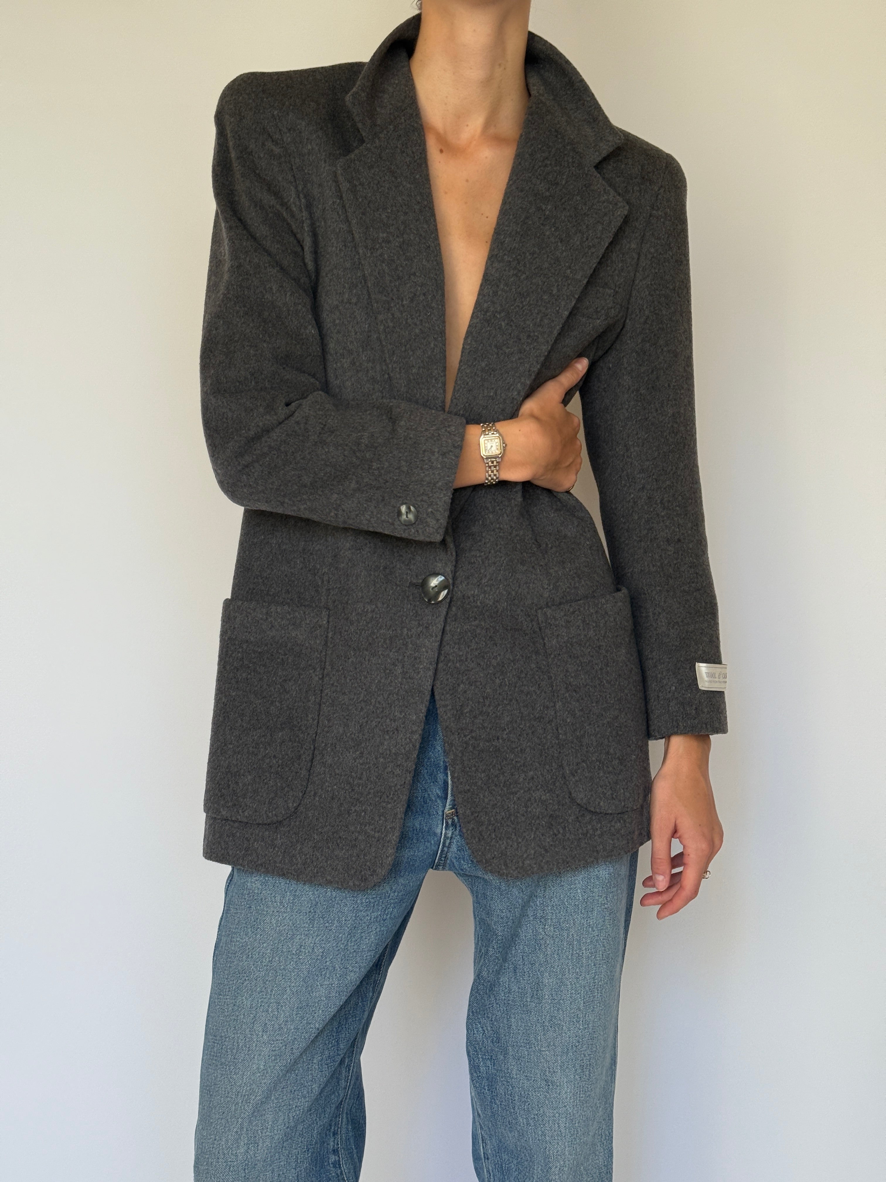 Front view of a vintage charcoal wool blazer styled open with denim jeans