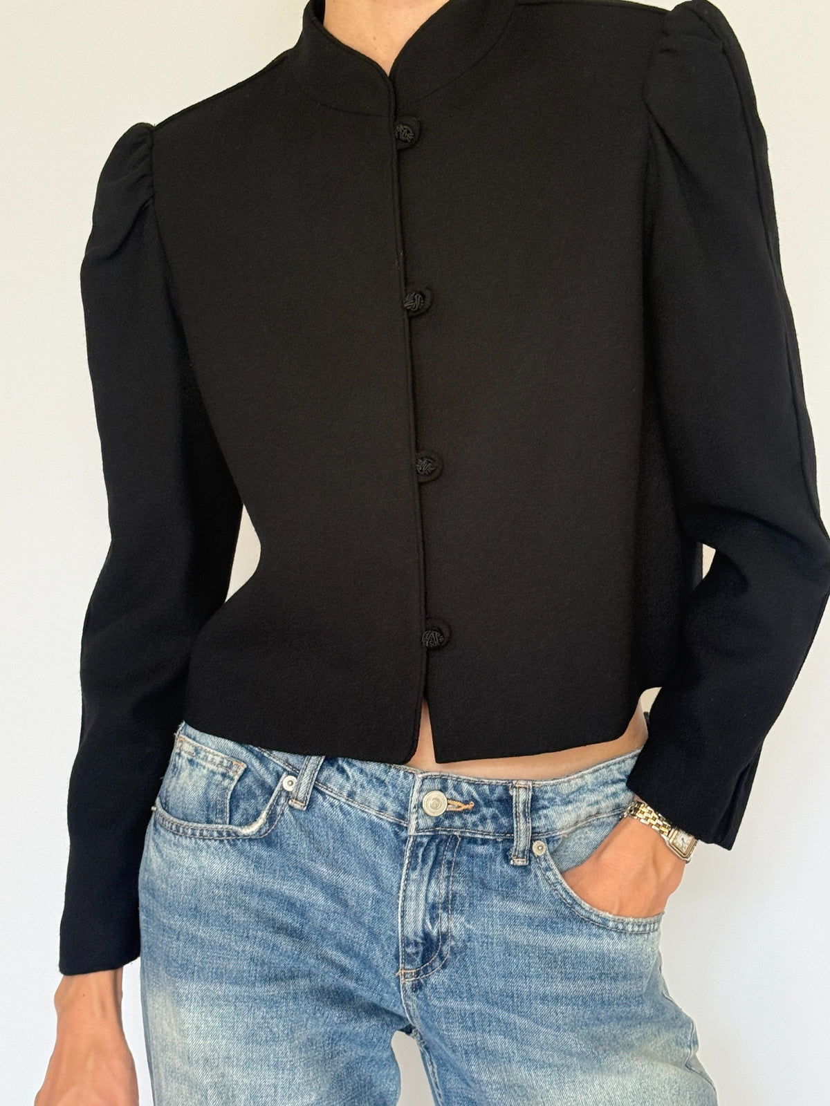 Vintage black wool jacket front view with stand collar, puff shoulders and frog closures