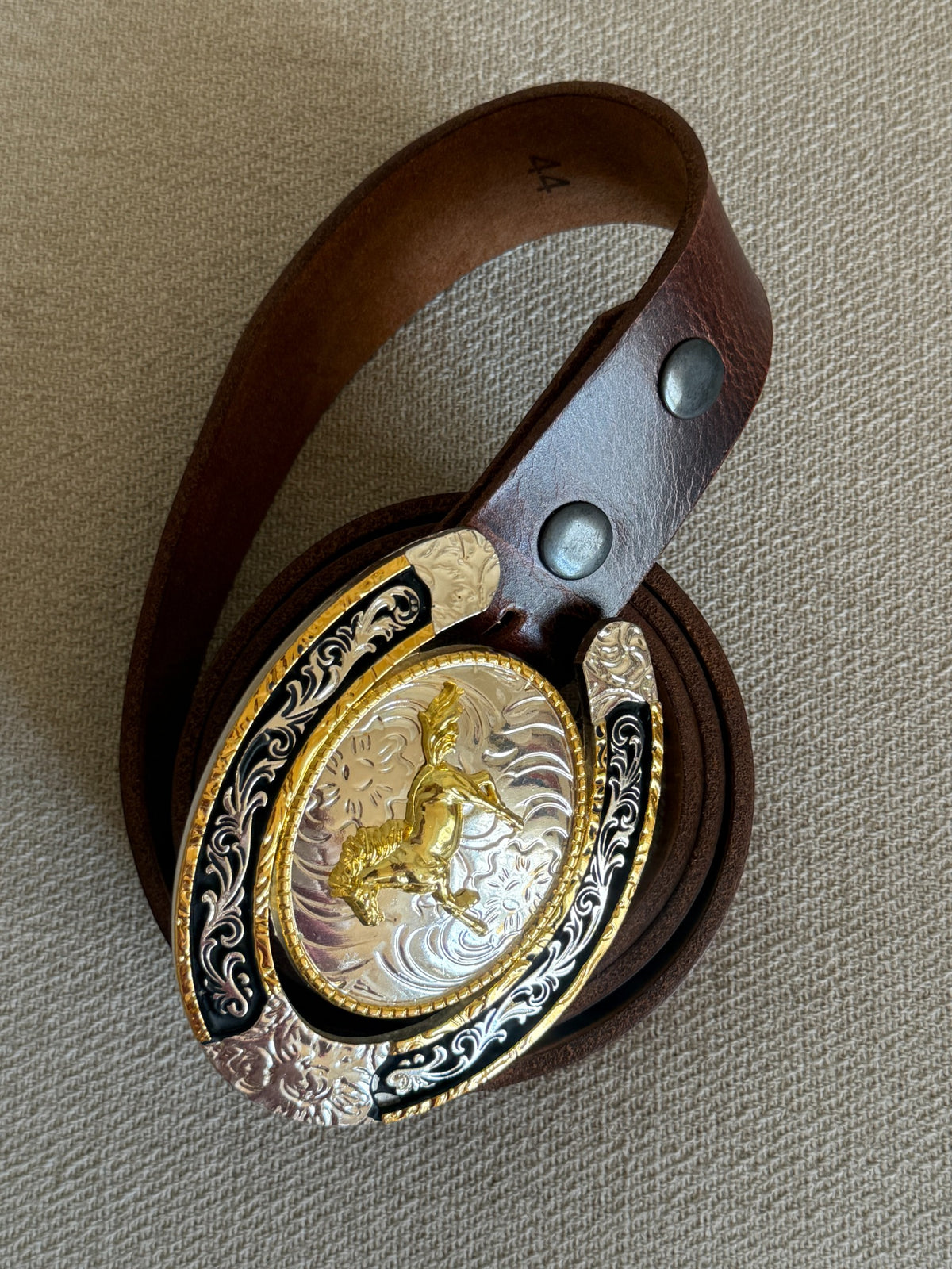 Vintage western leather belt coiled with horse horseshoe buckle