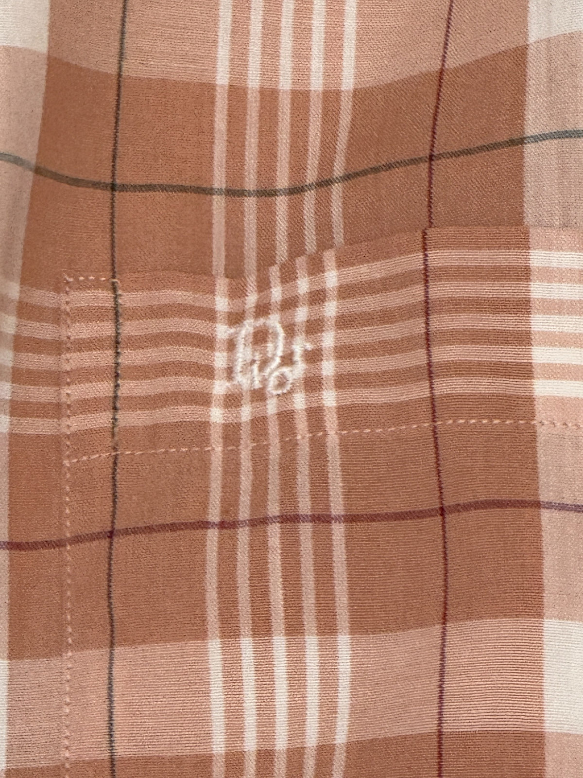 Close-up embroidered Christian Dior monogram on plaid chest pocket