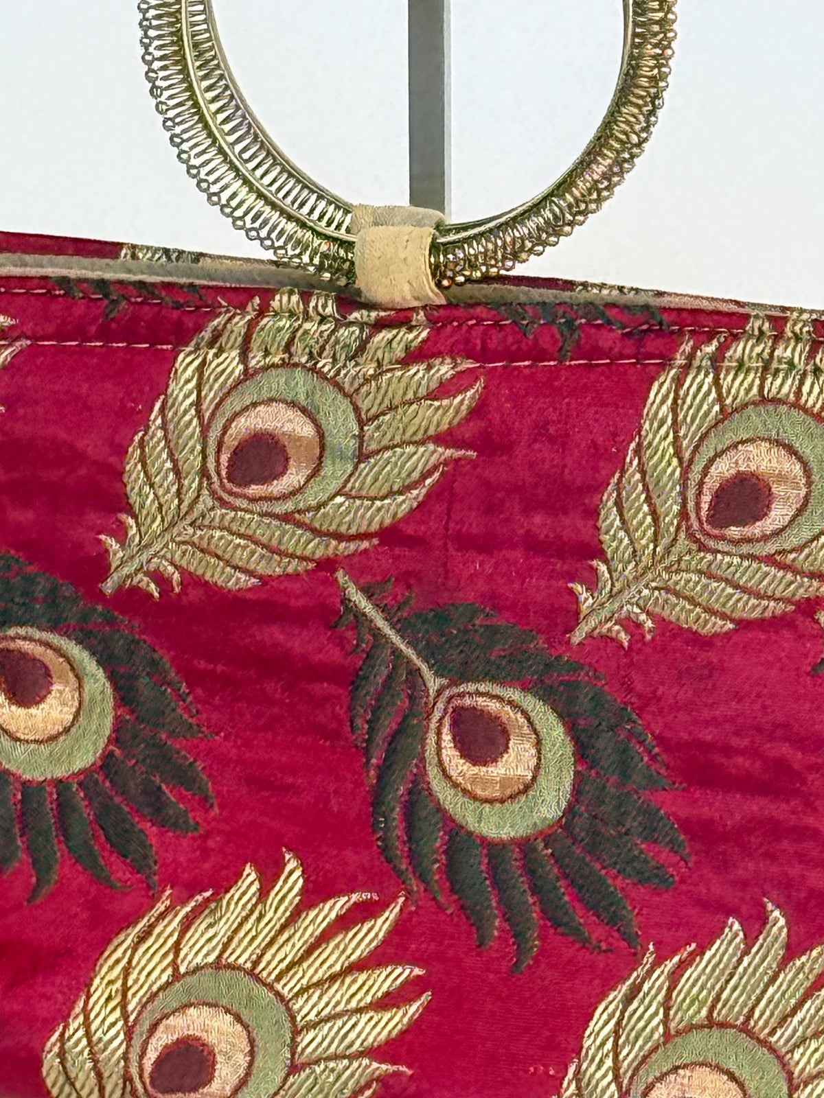 Close up peacock feather pattern and gold metal ring handle