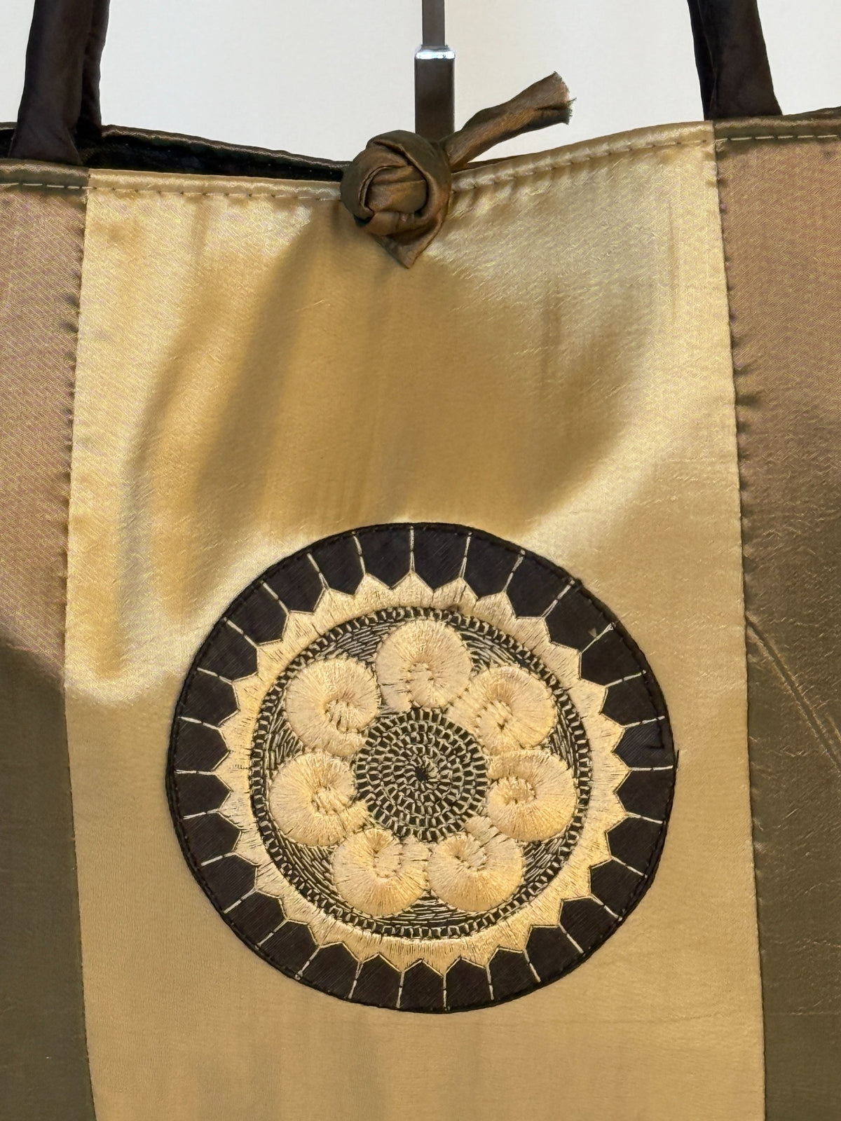Close-up of circular floral medallion embroidery on gold panel