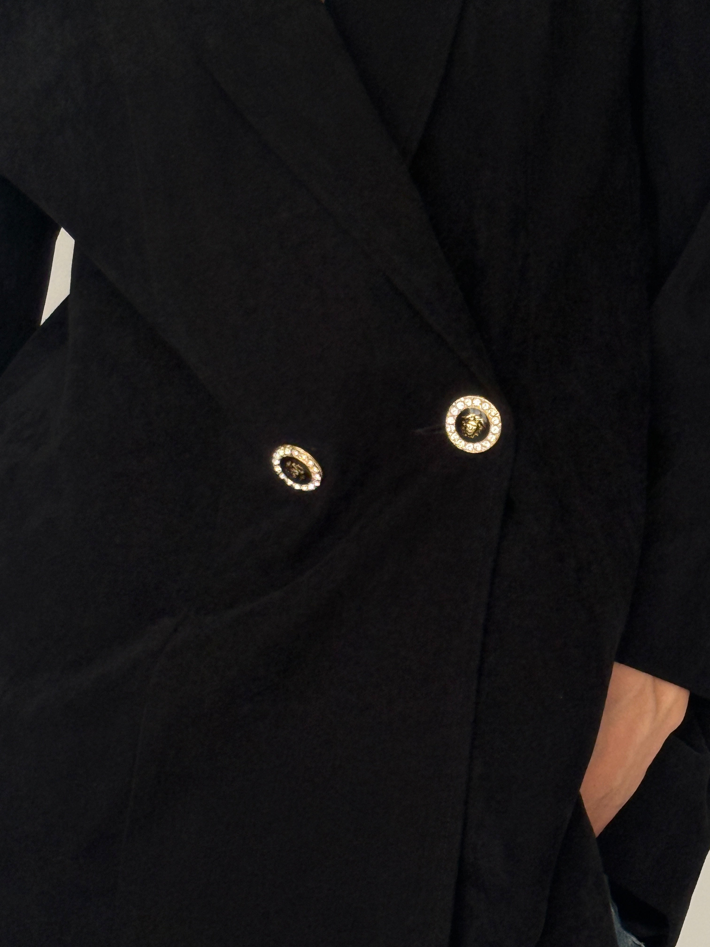 Vintage black blazer close-up showing decorative gold-tone buttons