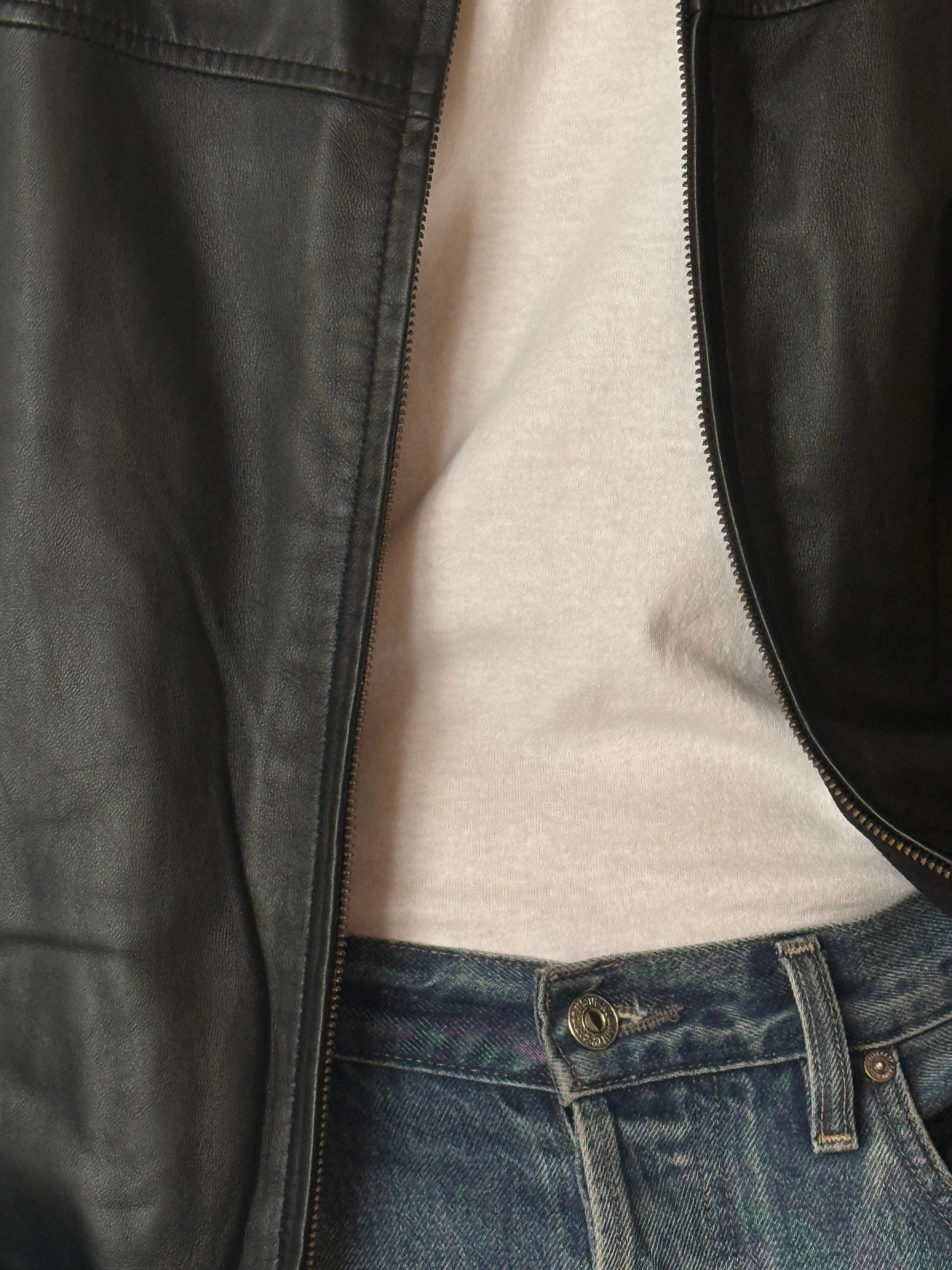 Vintage black leather jacket with subtle worn-in patina and soft finish close-up