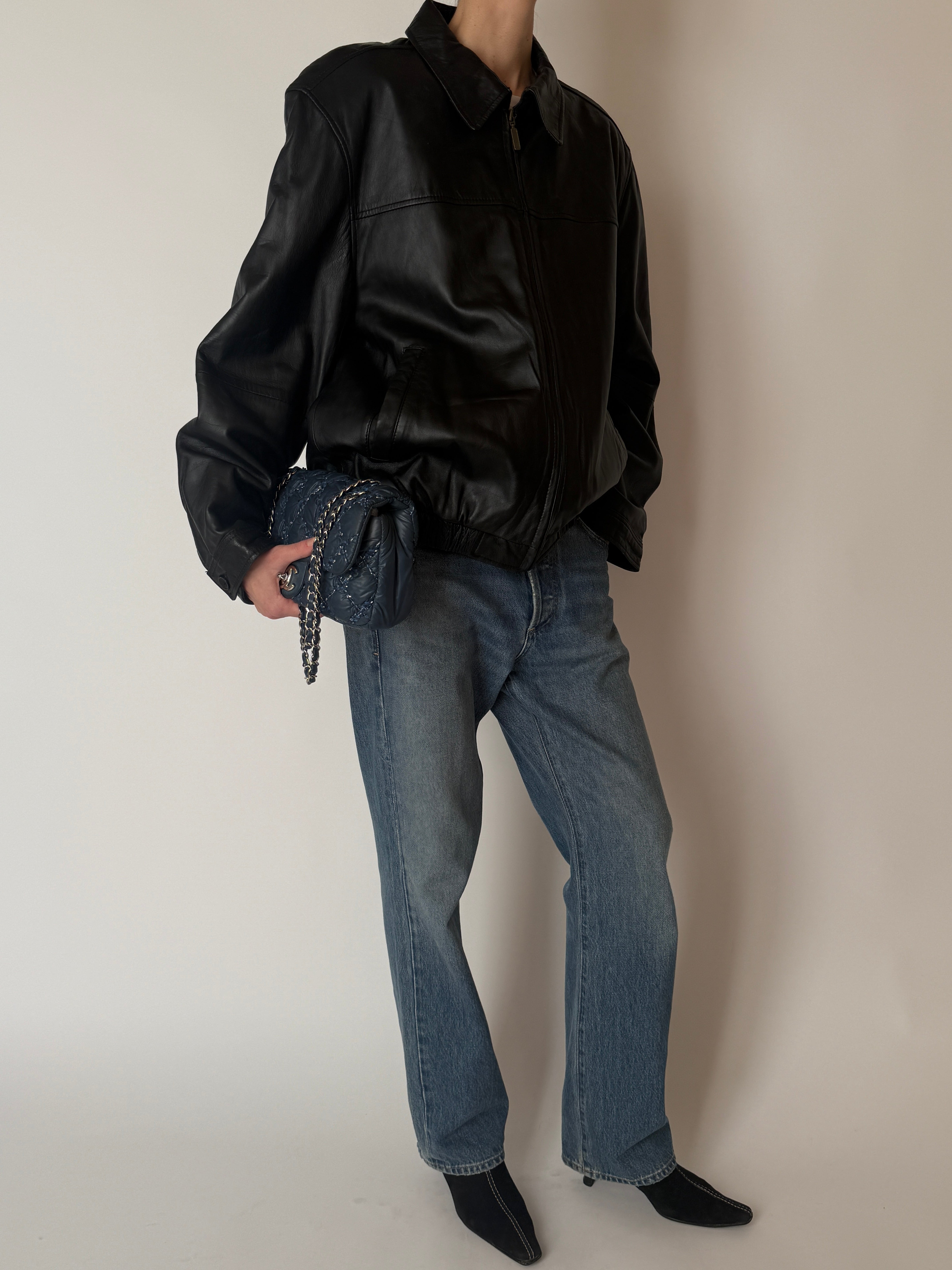 Vintage black leather jacket featuring a relaxed blouson silhouette full body side view