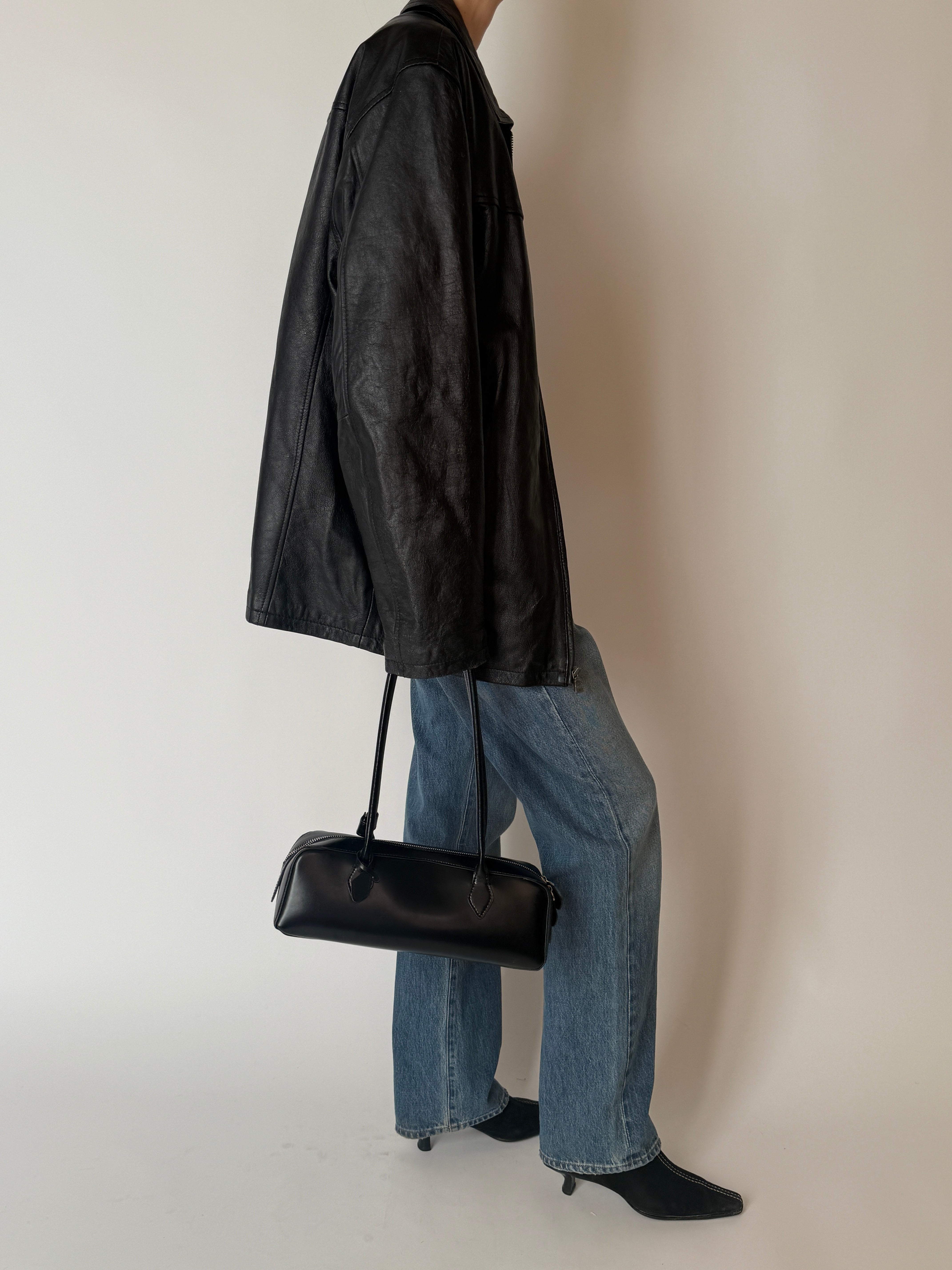 Vintage black leather jacket side view with zip-front closure
