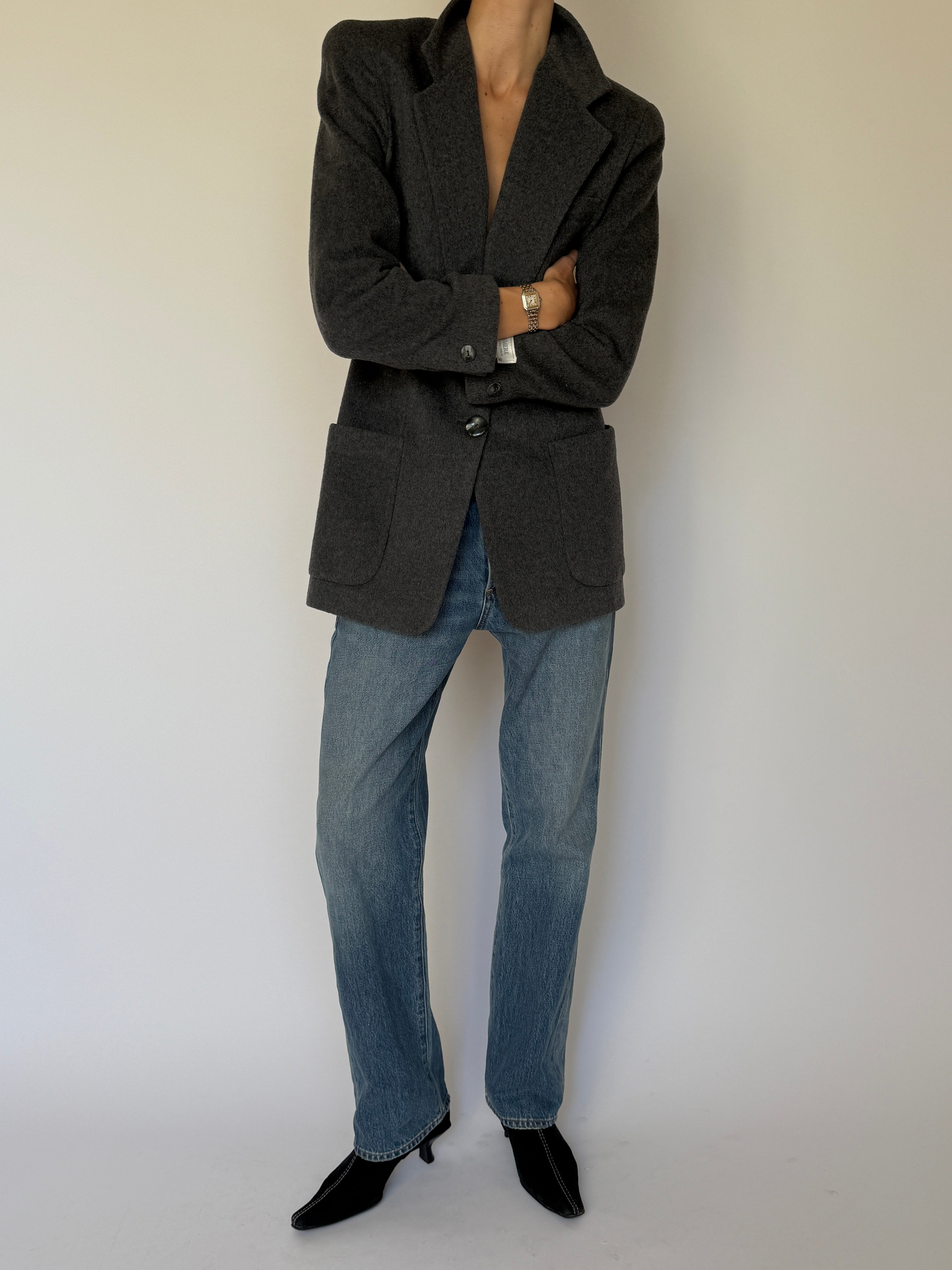 Front view of a vintage charcoal wool blazer styled open with denim jeans