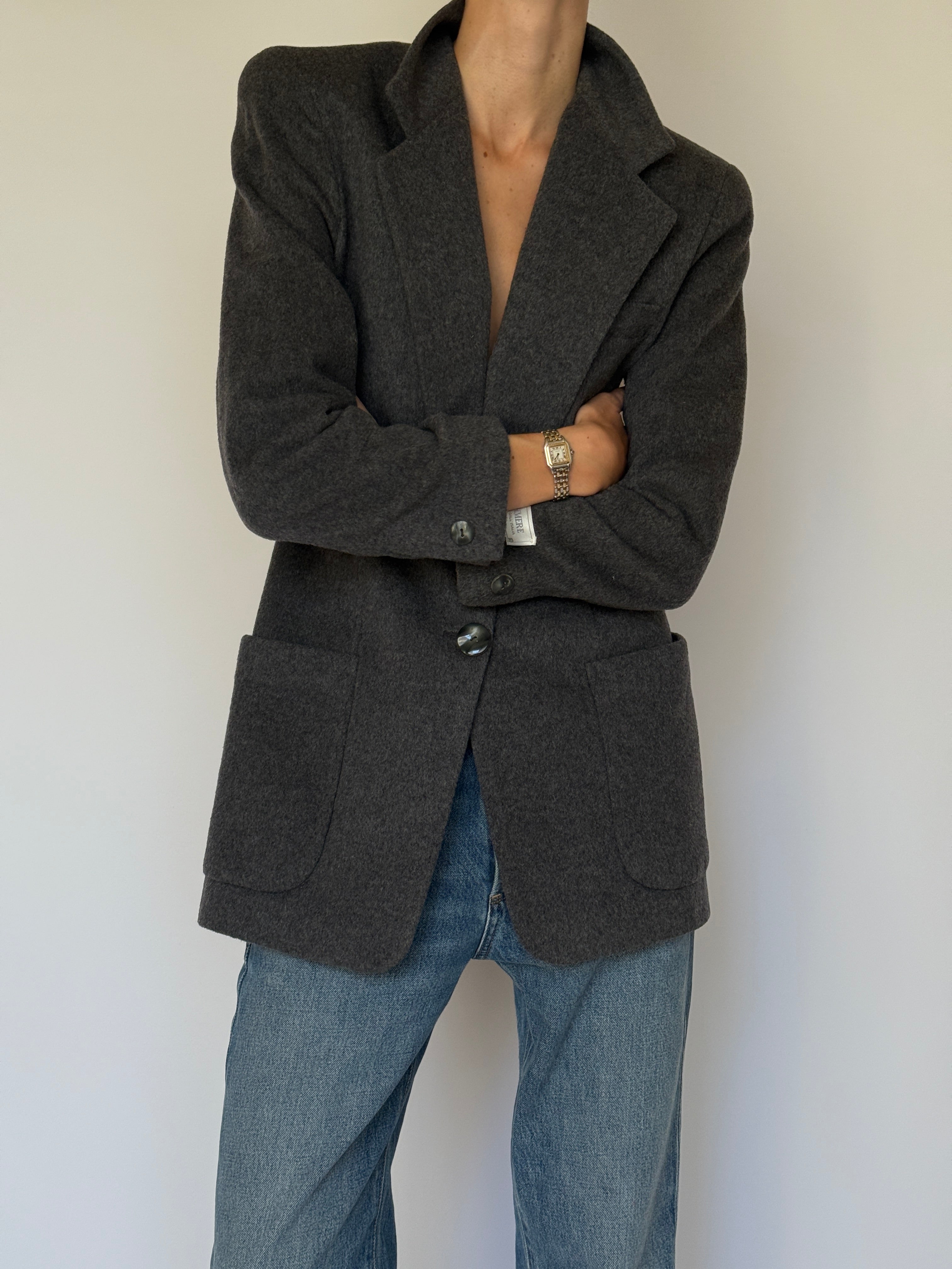 Front view of a vintage charcoal wool blazer styled open with denim jeans
